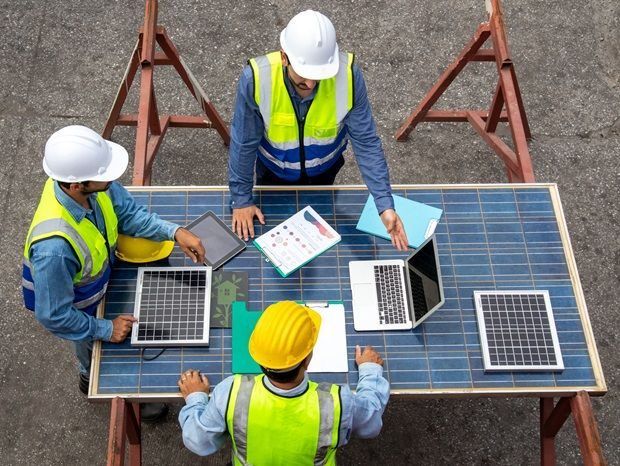 Equipo técnico revisando planos junto a paneles solares